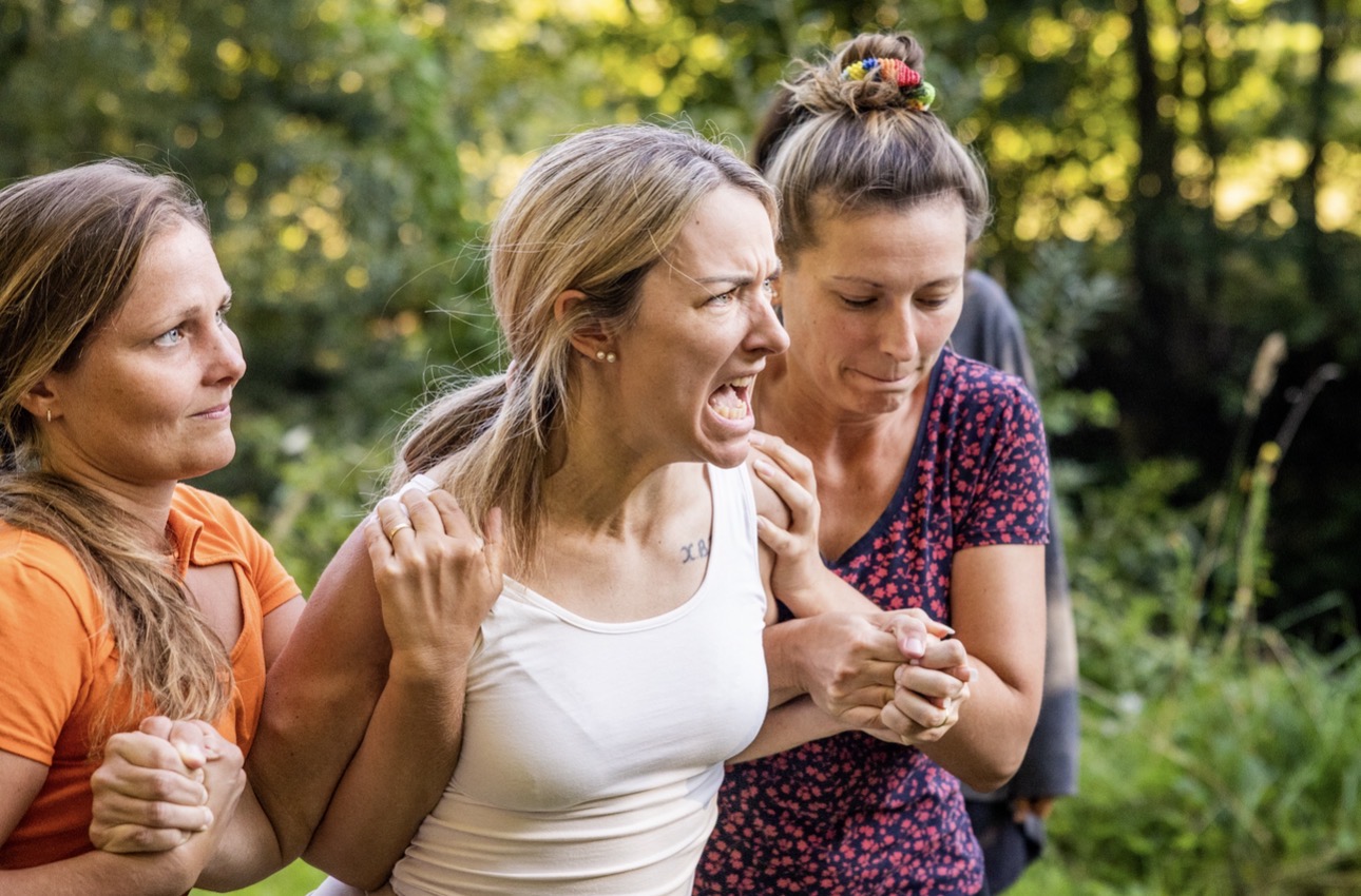 Frauen draußen in einer intensiven Embodiment-Übung, die sich gegenseitig halten